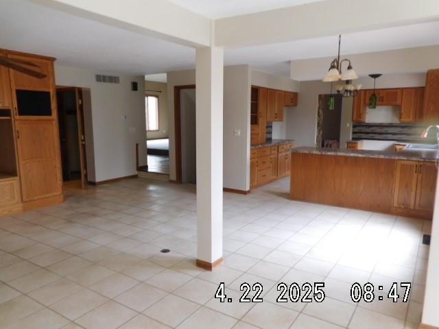 6680 John Dr, Mt Zion, IL 62549 - kitchen with brown cabinetry, open floor plan, a peninsula, and decorative light fixtures