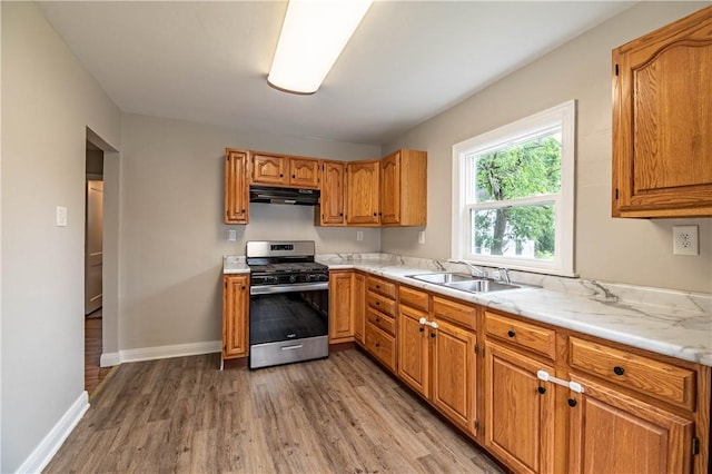 2036 E Dickinson Ave, Decatur, IL 62521 - kitchen featuring stainless steel range with gas cooktop, under cabinet range hood, light wood-style flooring, light countertops, and brown cabinetry
