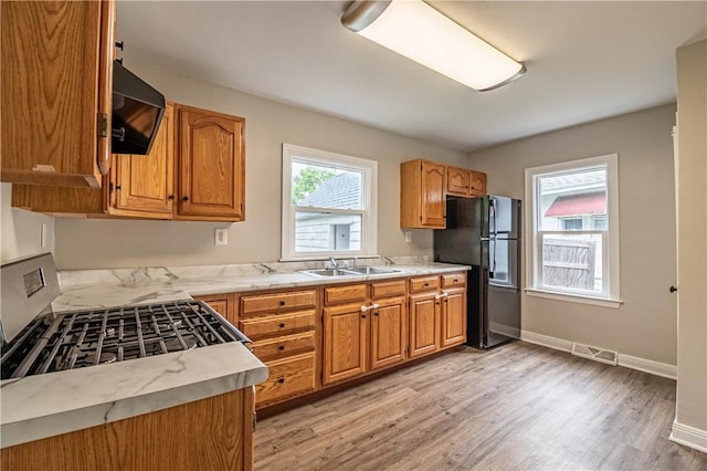 2036 E Dickinson Ave, Decatur, IL 62521 - kitchen featuring freestanding refrigerator, exhaust hood, light countertops, light wood-type flooring, and brown cabinetry