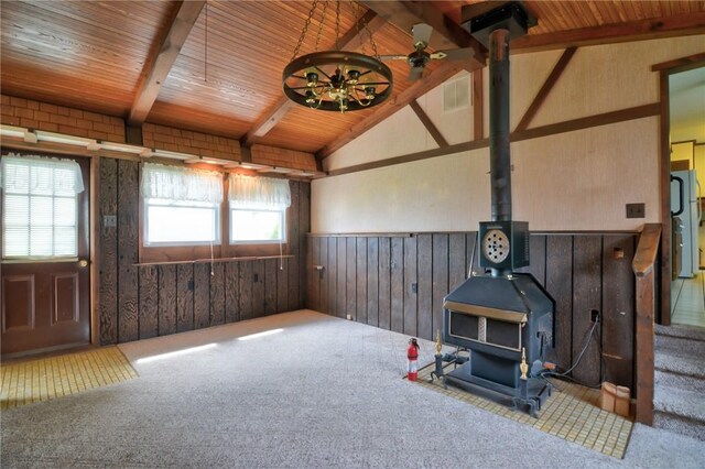 707 S Airport Rd, Decatur, IL 62521 - carpeted living area featuring a wood stove, a wainscoted wall, plenty of natural light, ceiling fan, and wood walls