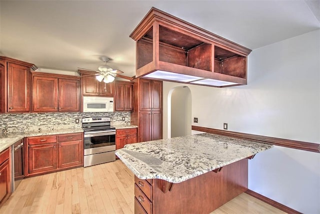 935 Woodland Dr, Mt Zion, IL 62549 - kitchen featuring appliances with stainless steel finishes, ceiling fan, decorative backsplash, arched walkways, and light stone counters