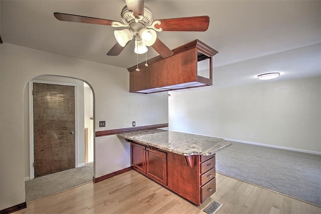 935 Woodland Dr, Mt Zion, IL 62549 - kitchen with a peninsula, ceiling fan, reddish brown cabinets, arched walkways, and light wood finished floors