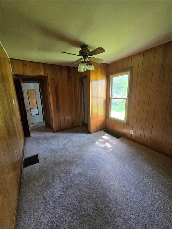 708 E Washington St, Clinton, IL 61727 - empty room featuring wooden walls, carpet flooring, and ceiling fan