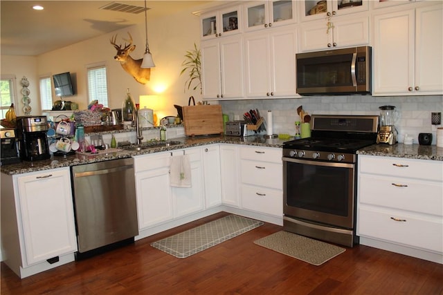 kitchen with appliances with stainless steel finishes, a sink, a peninsula, white cabinets, and recessed lighting