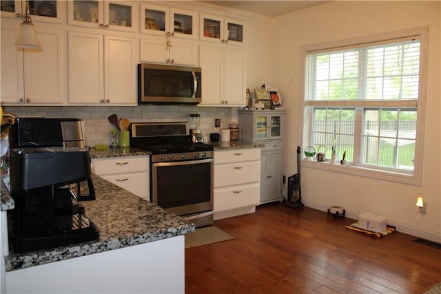 kitchen featuring stainless steel appliances, dark wood finished floors, white cabinets, and decorative backsplash