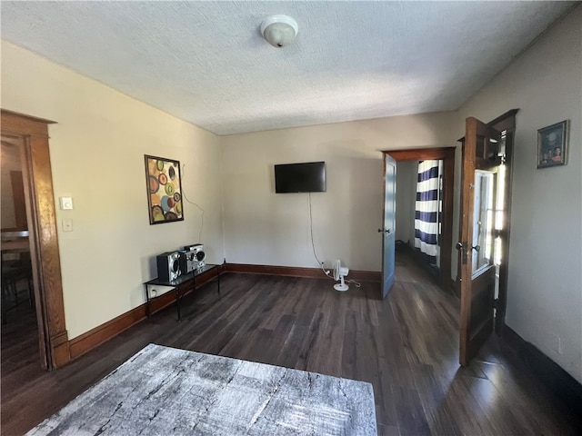 unfurnished living room with a textured ceiling and dark wood-type flooring