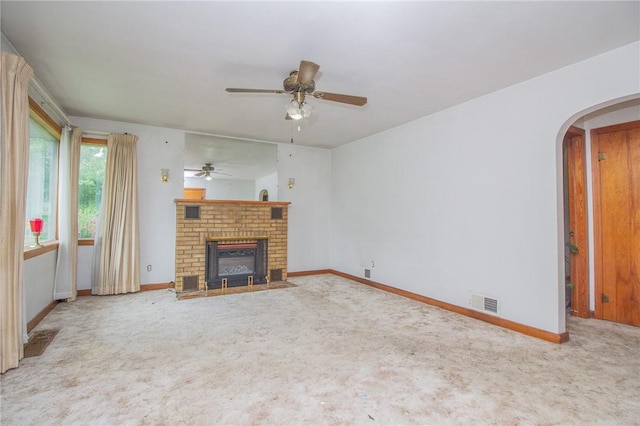 820 Oklahoma Ave, Mattoon, IL 61938 - unfurnished living room featuring carpet floors, arched walkways, a ceiling fan, and a brick fireplace