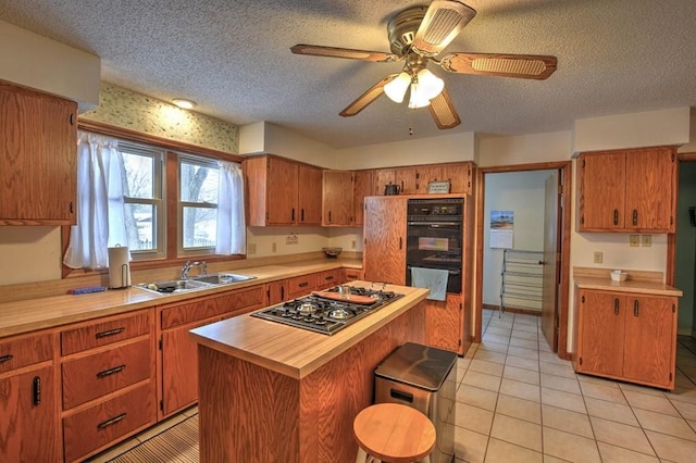 993 Cedar Hill Dr, Decatur, IL 62521 - kitchen featuring a sink, stainless steel gas stovetop, a textured ceiling, a breakfast bar, and brown cabinetry