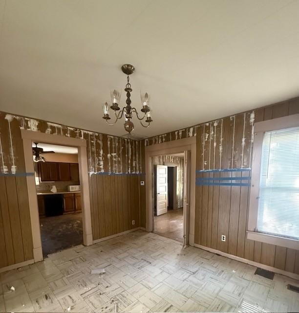 719 E Jefferson Ave, Chrisman, IL 61924 - unfurnished dining area featuring wood walls, a chandelier, and ceiling fan
