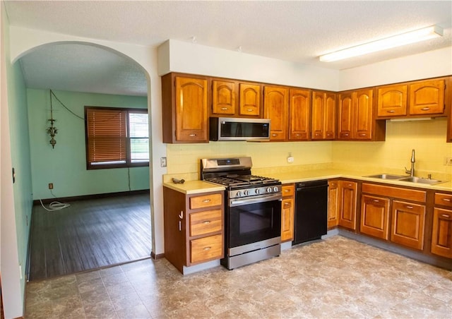 1021 Sunset Rdg, Danville, IL 61832 - kitchen featuring appliances with stainless steel finishes, arched walkways, a sink, light countertops, and brown cabinets