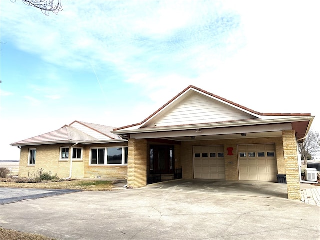 single story home with driveway, a garage, and brick siding