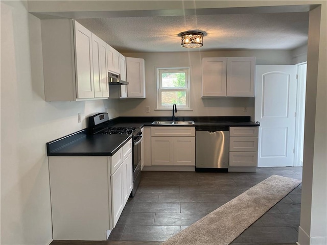 101 S Sheridan St, Pana, IL 62557 - kitchen with appliances with stainless steel finishes, a sink, under cabinet range hood, dark countertops, and a textured ceiling