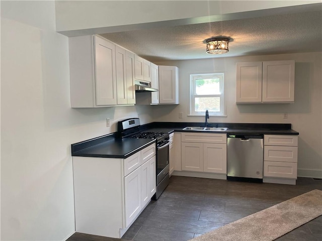 101 S Sheridan St, Pana, IL 62557 - kitchen with appliances with stainless steel finishes, a sink, under cabinet range hood, dark countertops, and a textured ceiling