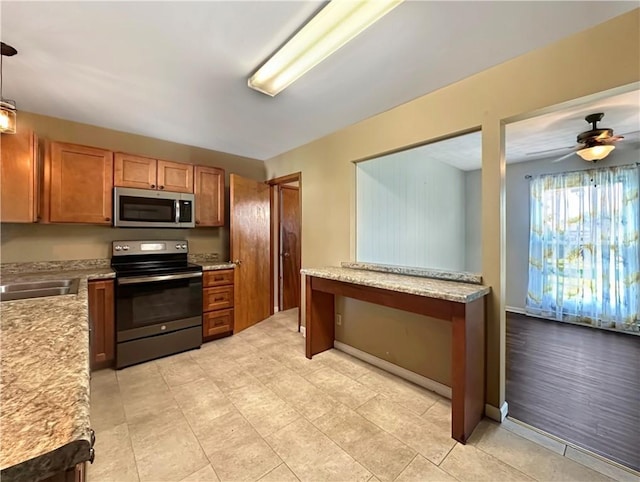 723 Kenton Dr, Charleston, IL 61920 - kitchen featuring appliances with stainless steel finishes, brown cabinetry, ceiling fan, and decorative light fixtures