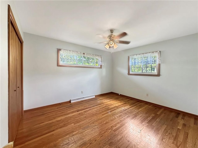 723 Kenton Dr, Charleston, IL 61920 - unfurnished bedroom with a baseboard radiator, a closet, wood finished floors, and a ceiling fan