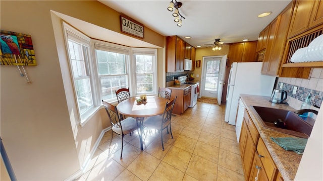 kitchen featuring a sink, white appliances, tasteful backsplash, and brown cabinets