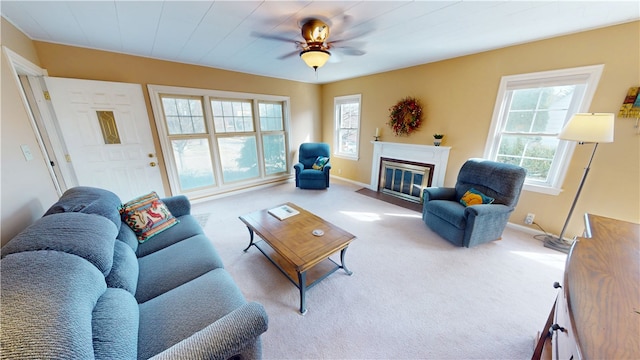 living area with a fireplace with flush hearth, a ceiling fan, baseboards, and carpet floors