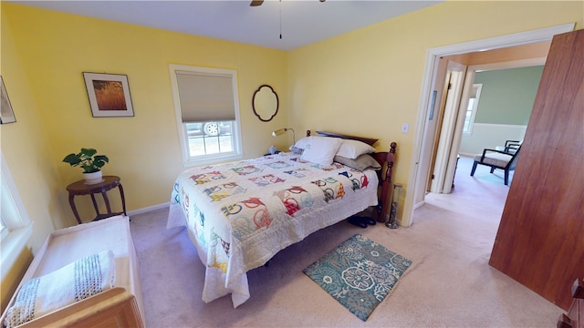 bedroom featuring light carpet, a ceiling fan, and baseboards