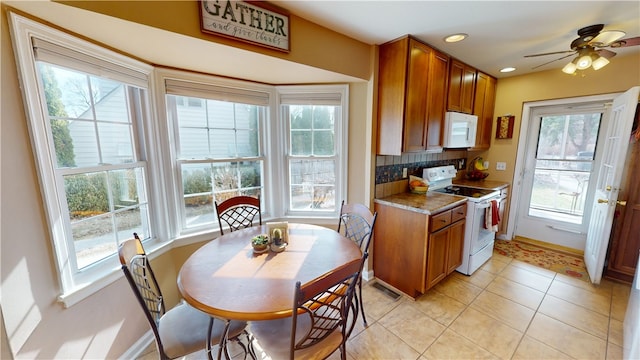 kitchen with white appliances, light tile patterned flooring, brown cabinetry, and tasteful backsplash