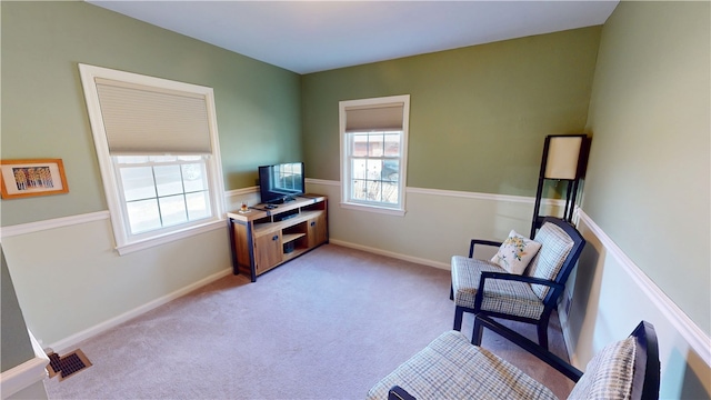 sitting room with light colored carpet, visible vents, and baseboards