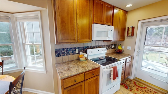 kitchen featuring light stone counters, decorative backsplash, white appliances, and brown cabinetry