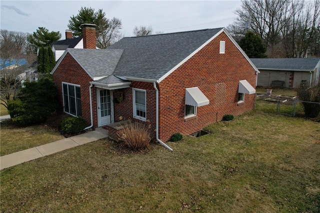 view of front of house featuring fence, a shingled roof, a chimney, a front lawn, and brick siding