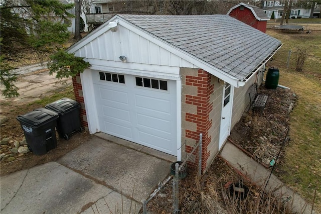 garage featuring concrete driveway and fence