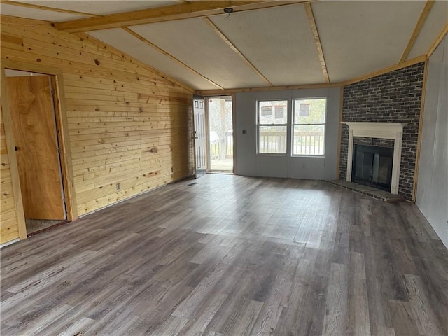 unfurnished living room featuring a fireplace, dark hardwood / wood-style floors, wood walls, and vaulted ceiling with beams