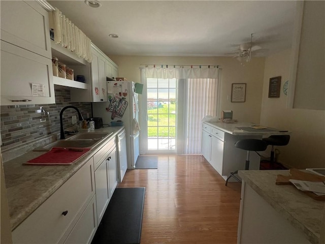1215 Westside Dr, Mt Zion, IL 62549 - kitchen with decorative backsplash, light wood-style flooring, white cabinetry, light countertops, and white dishwasher