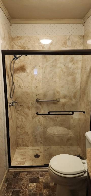 bathroom featuring toilet, a shower with door, and ornamental molding