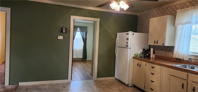 kitchen featuring wood counters, ornamental molding, ceiling fan, sink, and white refrigerator