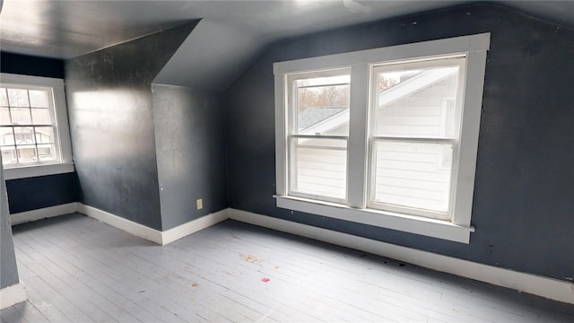 additional living space with vaulted ceiling and light hardwood / wood-style flooring