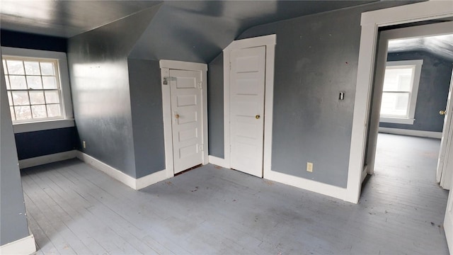 additional living space with light wood-type flooring and vaulted ceiling