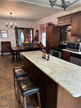 kitchen featuring dark brown cabinetry, pendant lighting, stainless steel appliances, and an inviting chandelier