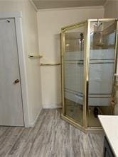 bathroom with vanity, wood-type flooring, ornamental molding, and walk in shower