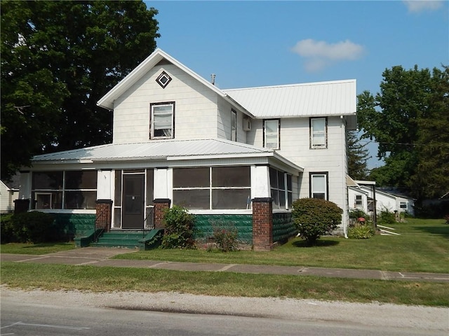 view of front facade featuring a front yard and a sunroom