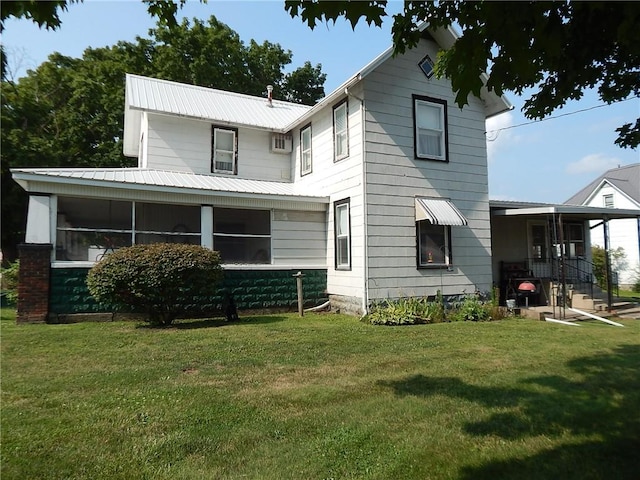 rear view of property featuring a sunroom and a lawn