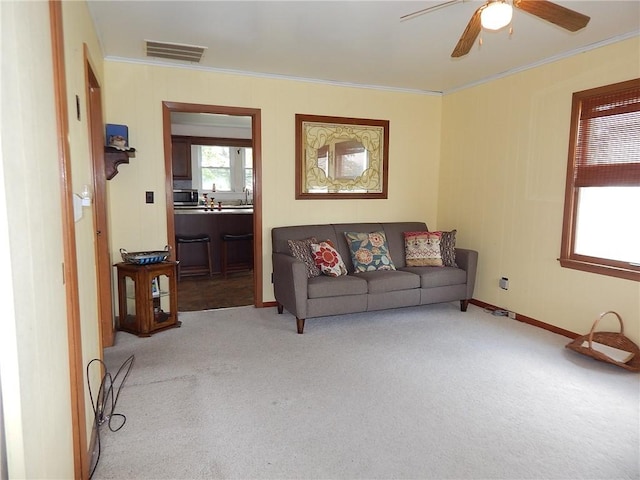 carpeted living room with crown molding and ceiling fan