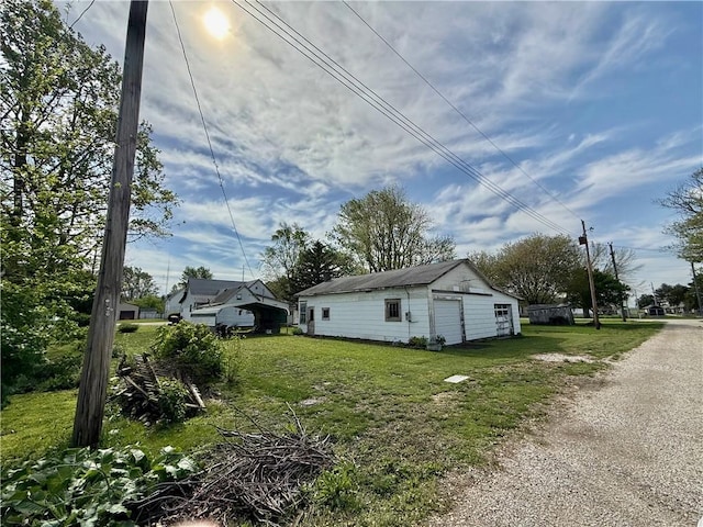 view of side of property featuring a lawn, an outdoor structure, and a detached garage