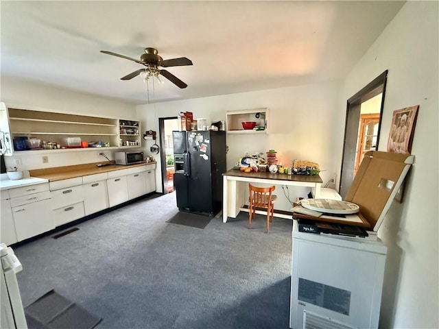 kitchen with open shelves, stainless steel microwave, white cabinets, a ceiling fan, and black fridge