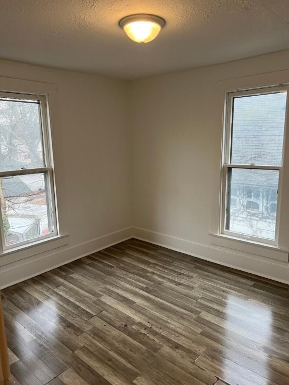 empty room featuring a textured ceiling and dark wood-type flooring