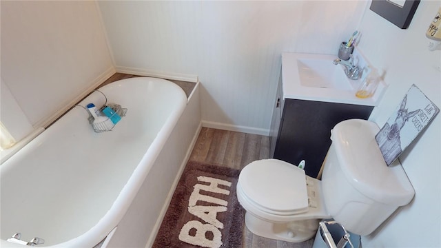 bathroom featuring a bathing tub, hardwood / wood-style flooring, vanity, and toilet