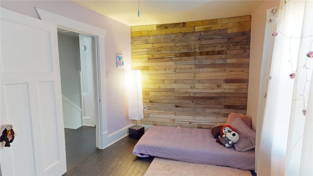 bedroom with dark hardwood / wood-style floors and wood walls