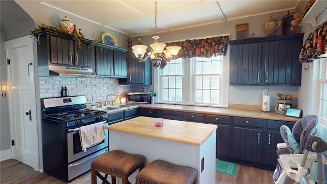 kitchen with an inviting chandelier, sink, blue cabinetry, light hardwood / wood-style floors, and stainless steel appliances