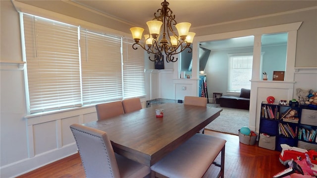 dining area with dark wood-type flooring, crown molding, and a chandelier