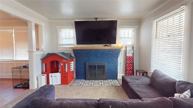 living room featuring hardwood / wood-style flooring, ornamental molding, and a brick fireplace