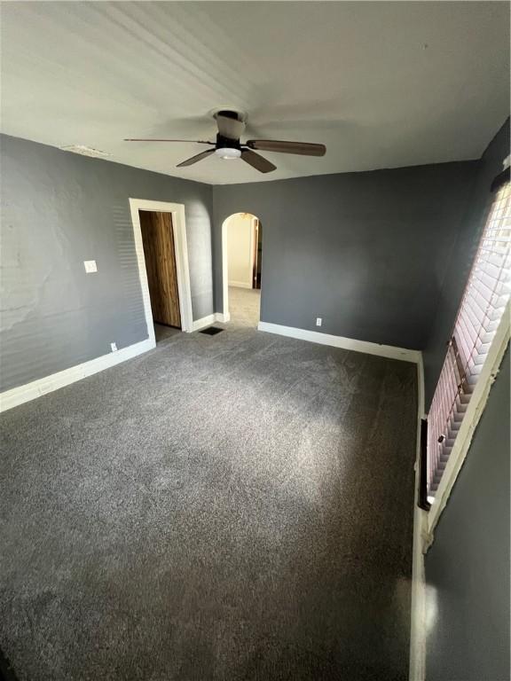 314 W Maple St, Hoopeston, IL 60942 - unfurnished bedroom with arched walkways, carpet floors, and a ceiling fan