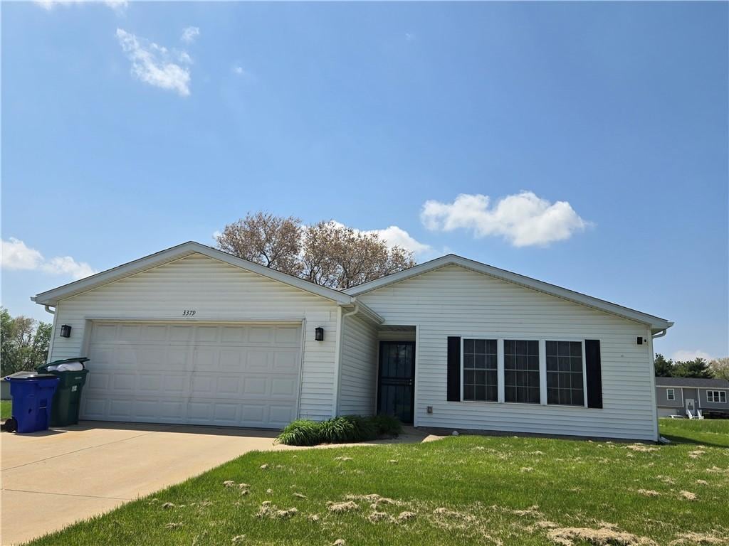 ranch-style home featuring an attached garage, driveway, and a front lawn