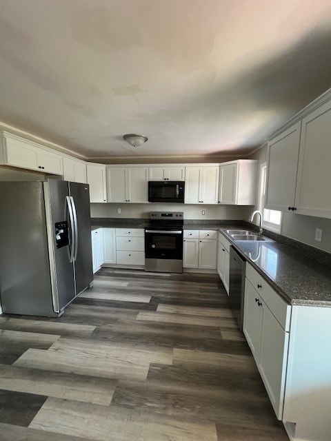 kitchen featuring white cabinetry, sink, dark wood-type flooring, stainless steel appliances, and dark stone counters