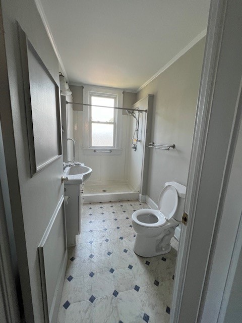 bathroom featuring toilet, vanity, ornamental molding, and tiled shower